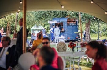 Corporate summer party guests mingling in a landscaped garden, enjoying drinks, conversation, and a relaxed outdoor atmosphere in a scenic venue setting.
